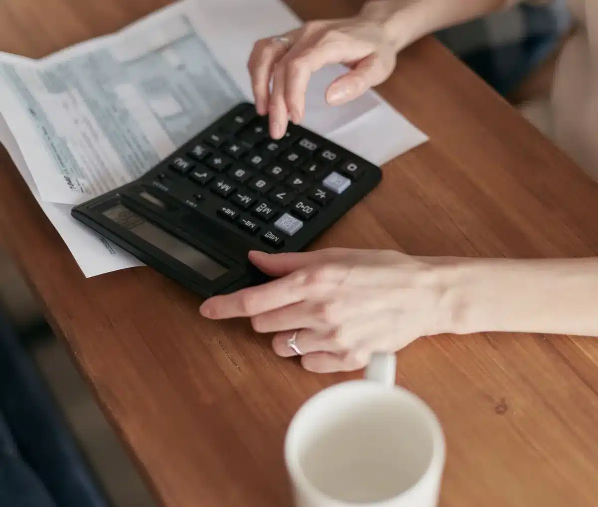 Scattered bills, loan documents, and a calculator on a desk representing late payments and financial debt