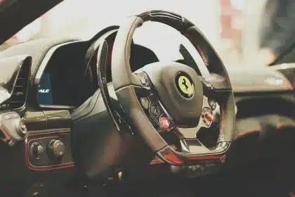 Interior view of a generic EV dashboard and hands using the infotainment screen in daylight showroom