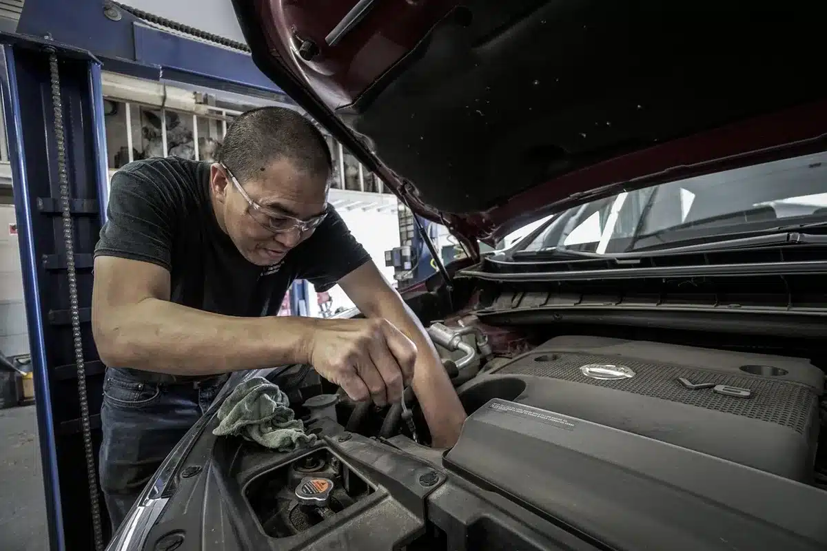 A young person working on a car engine in a well-lit garage