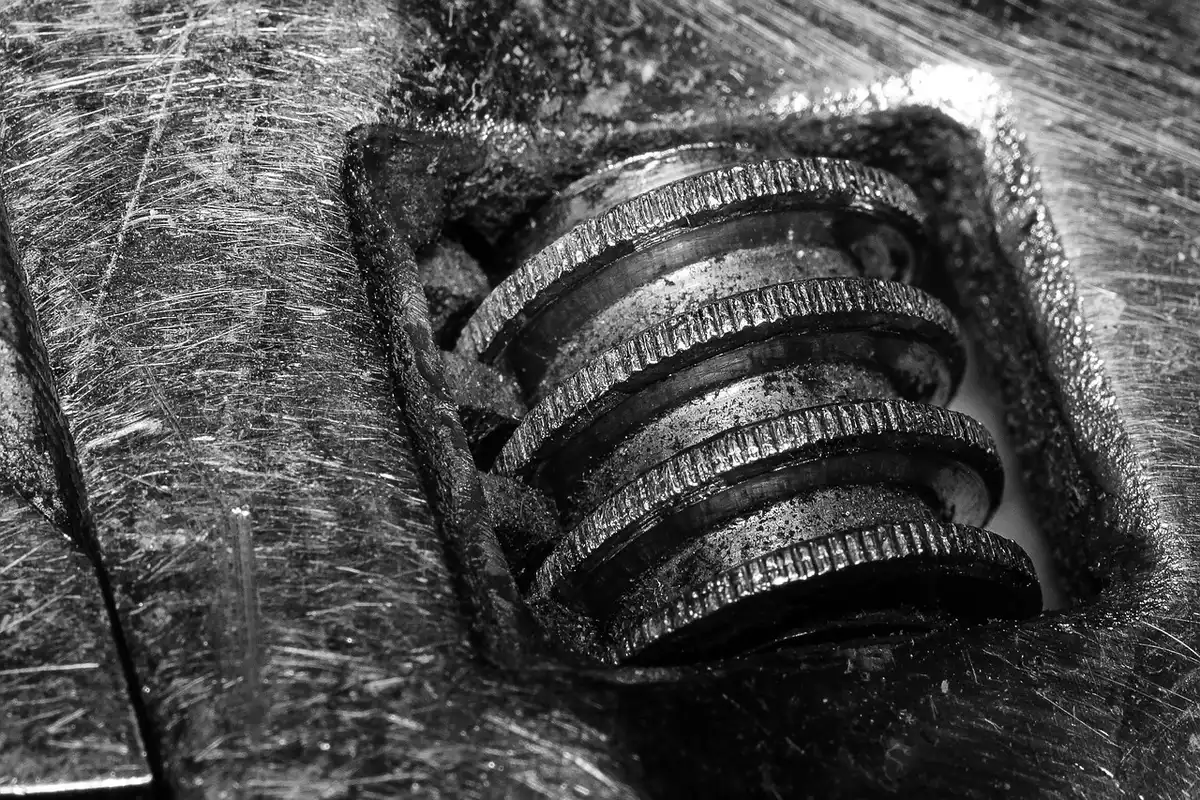Hands working on an older car engine in a home garage with tools on a bench
