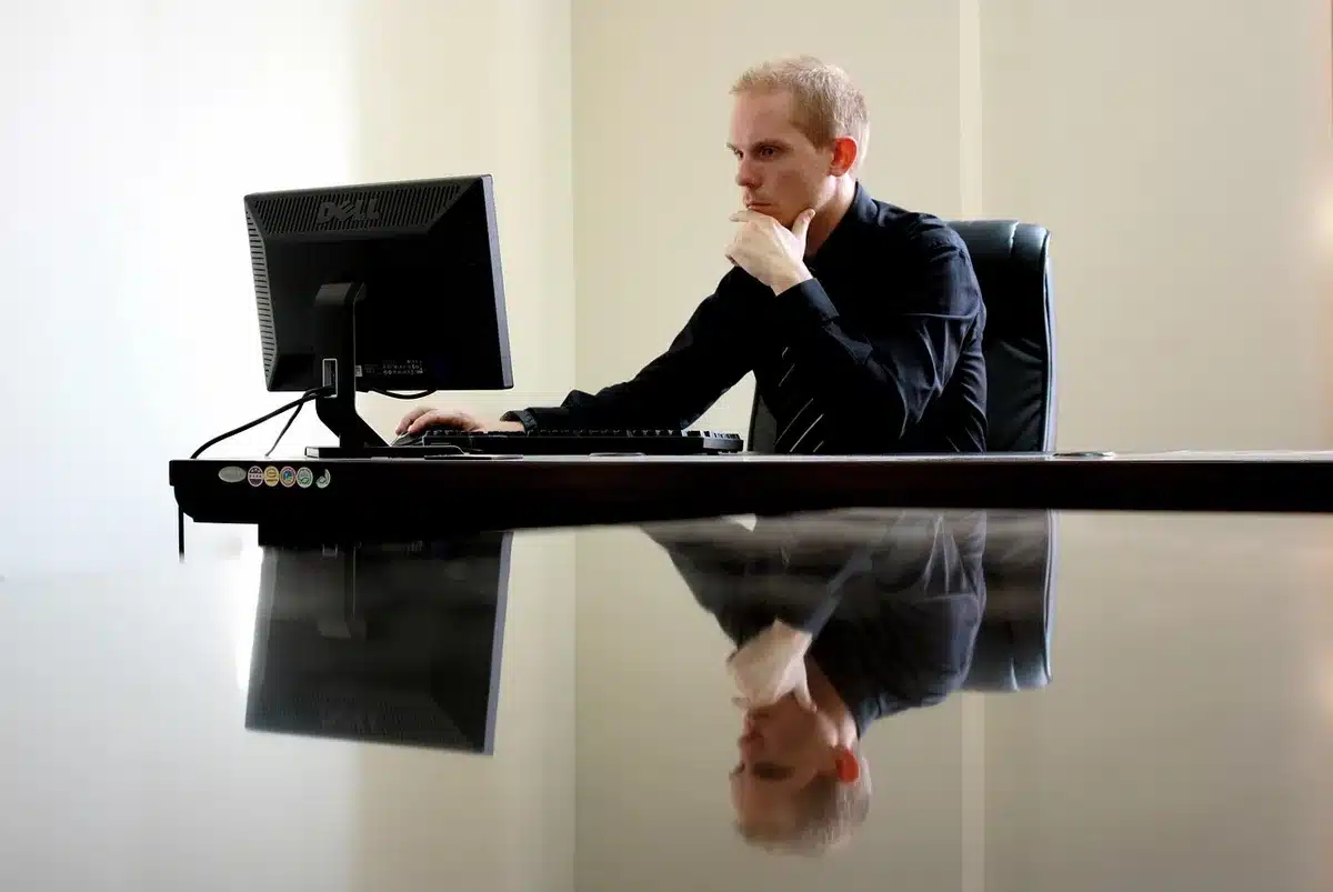Person working on laptop in a bright office considering compliance costs
