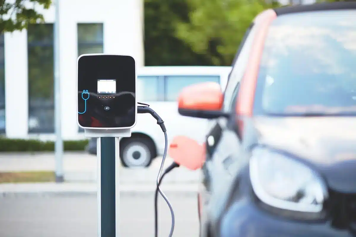 Bright showroom with electric cars and a charging cable being plugged in, daylight through windows