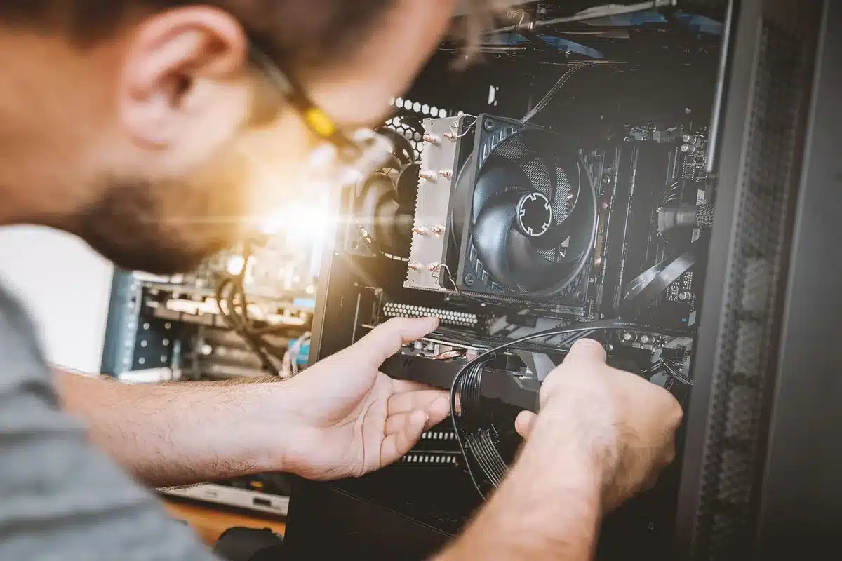 Engineer examining a small axial fan beside car components in a bright workshop