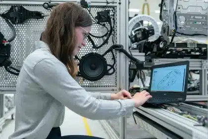 Bright workshop interior with an open car hood and laptop showing a parts diagram