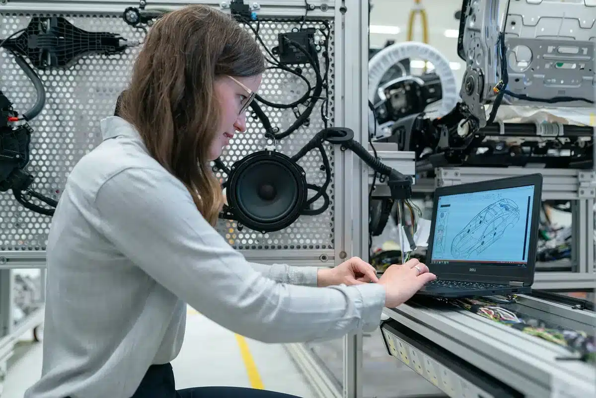 Bright workshop interior with an open car hood and laptop showing a parts diagram